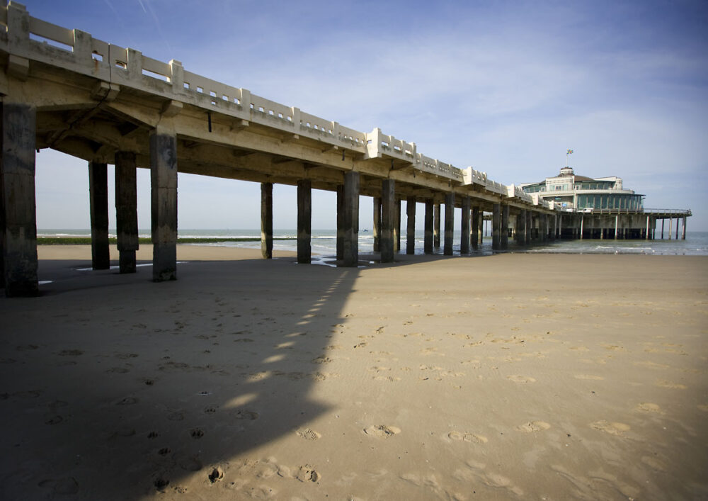 Belgium Pier stretching into the sea, reaching from the shore, its weathered planks extending into the azure expanse.