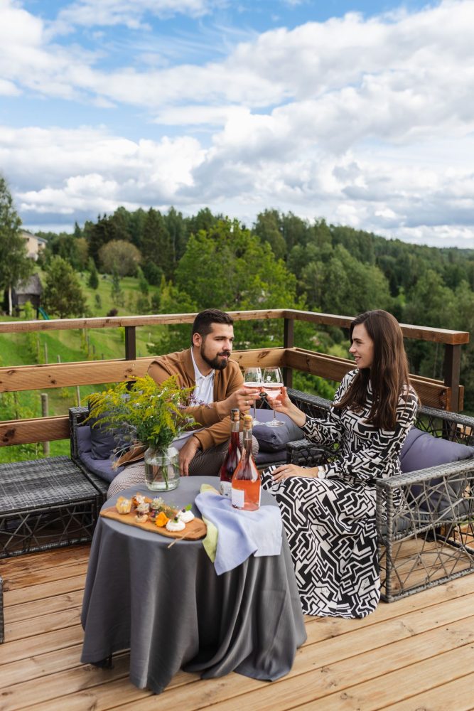 Couple enjoying rosé wine and snacks on the terrace of Murimäe Wine Cellar, surrounded by rolling hills.