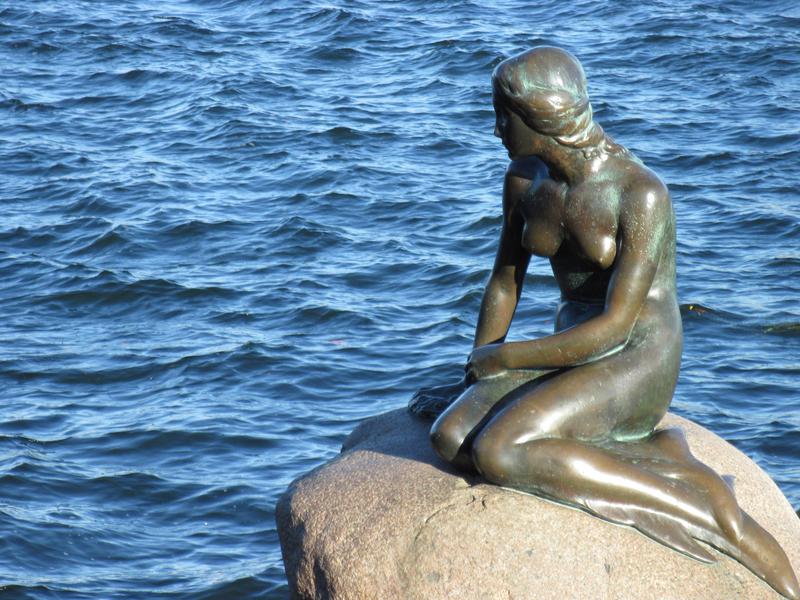 The statue inspired by The Little Mermaid overlooks the calm waters in Copenhagen, Denmark.