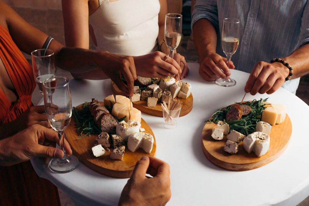 Friends enjoying local cheese and charcuterie tasting with glasses of wine at a social gathering in Europe.