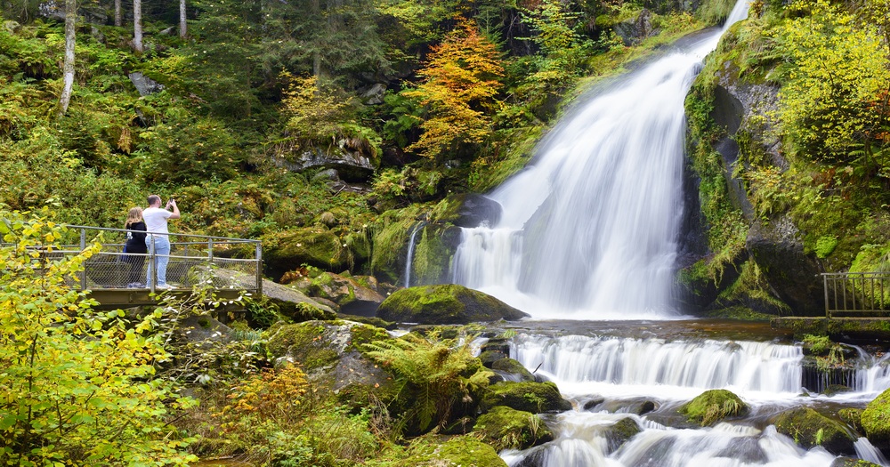 Visitors admiring the cascading Triberg Waterfalls framed by dense forest in the Black Forest, Germany.