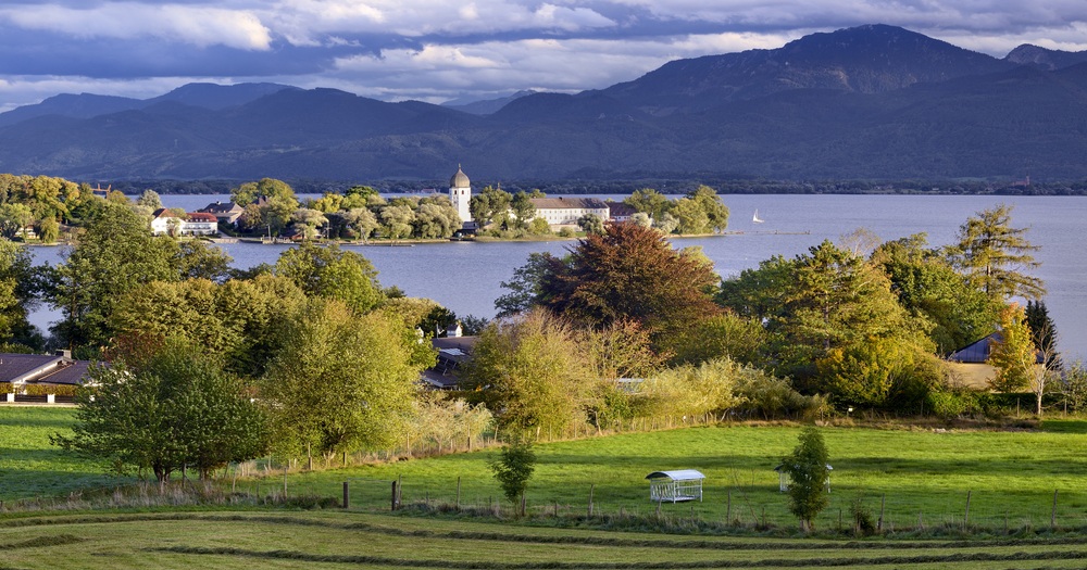 Scenic view of Lake Chiemsee with Frauenchiemsee Island and the Bavarian Alps in the background.