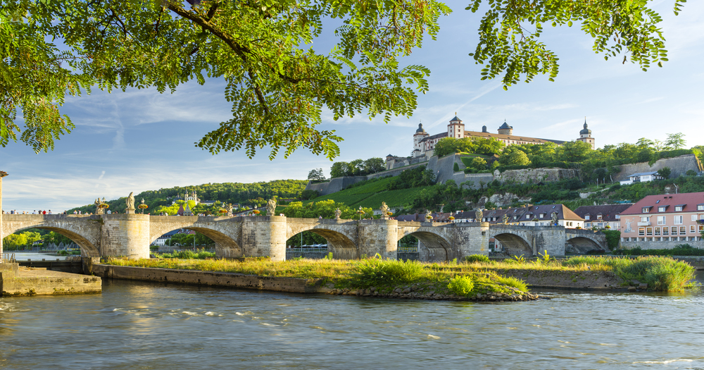 Old Main Bridge and the Marienberg Fortress in Würzburg, Germany, with vineyards and historic buildings overlooking the Main River.