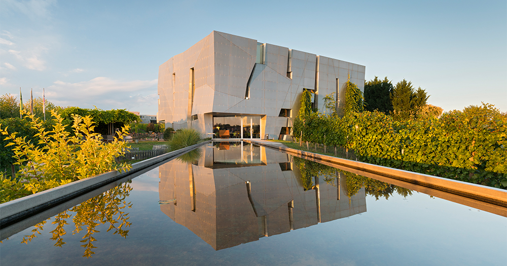 Modern LOISIUM WineWorld building in Austria, designed by architect Steven Holl, with vineyard reflections in the water feature.
