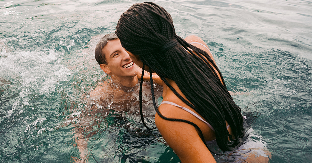 Smiling couple swimming together in a clear alpine lake.
