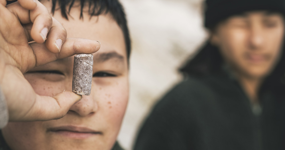 Close-up of a child holding a fossil at Møns Klint, Denmark, with another child blurred in the background.