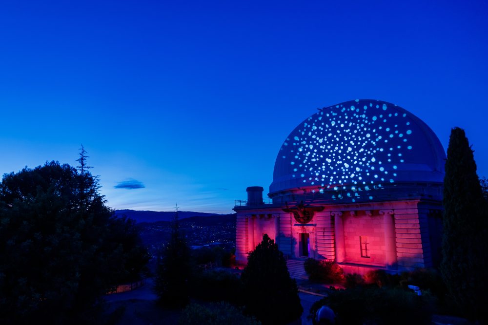 Nice Observatory illuminated with star-shaped projections against a deep blue winter sky, highlighting its architectural elegance.