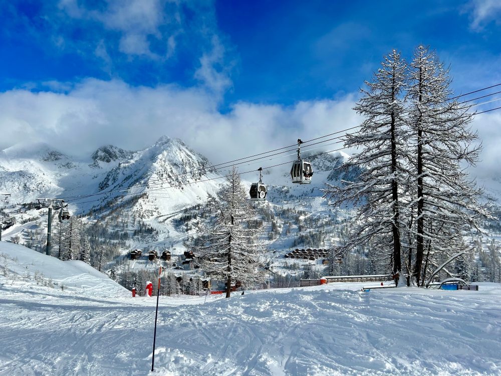 Snow-covered slopes and ski lifts at Isola 2000 in the French Alps, with pristine white mountains under a clear blue sky.