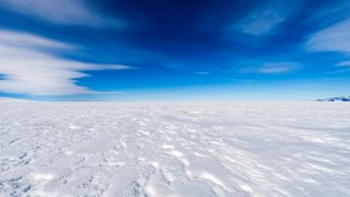 The Ross Ice Shelf, an expanse of ice, with a blue sky and clouds above