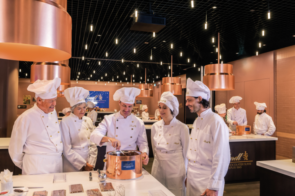 Chocolate factory workers dressed in uniforms preparing chocolate at the Lindt company.